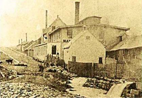 "This photo shows the bed of the inclined rail plane beside the Starr Manufacturing Plant. The peaked roof showing above the middle of the plant is the roof of the Flume House. The Starr plant was built around the Flume House and utilized the flume for power." Text and photo from the tender document, linked to below.