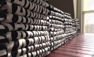 Several stacks of neatly folded halifax Examiner shirts lined up in a row on a sunny table