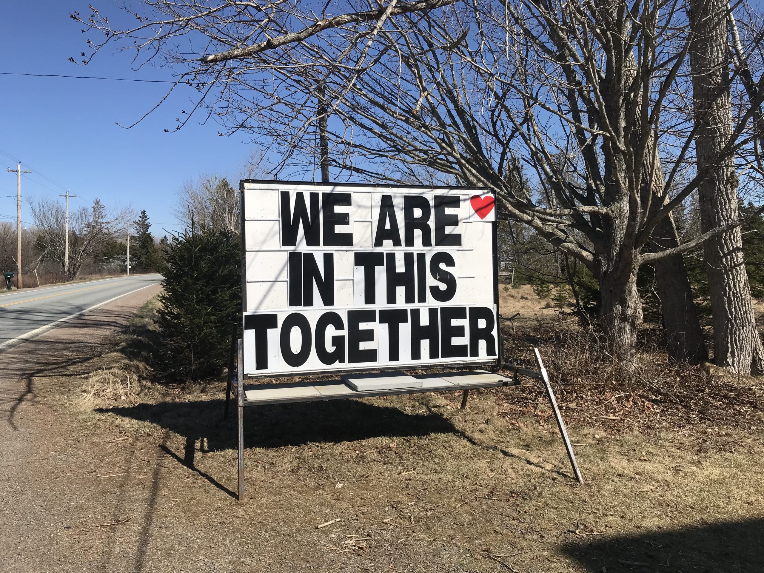 Moveable roadside sign reading "We are in this together"