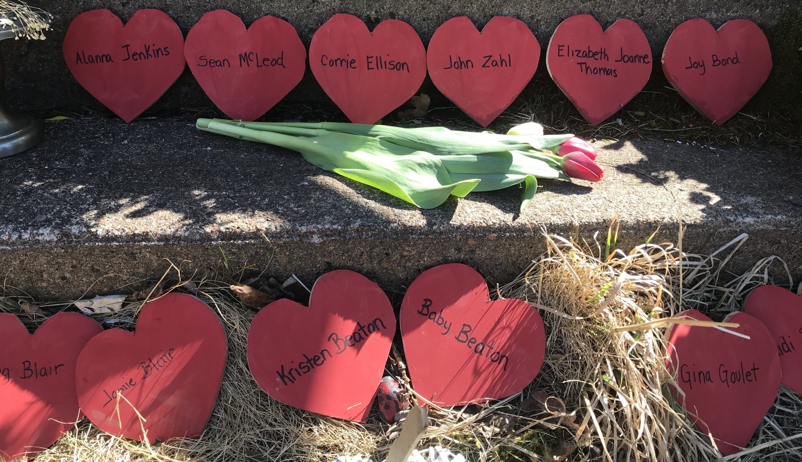 A memorial on the church steps, for victims of the mass shooter, with red paper hearts and tulips