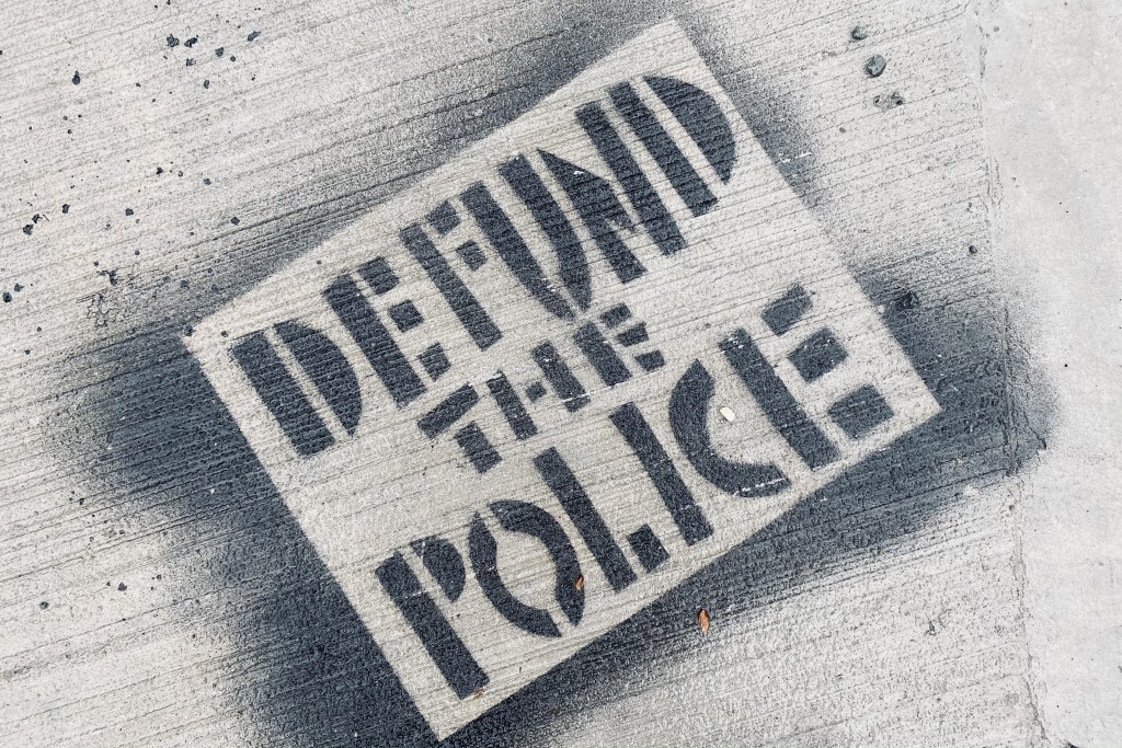 A black stenciled "defund the police" image on a Halifax sidewalk