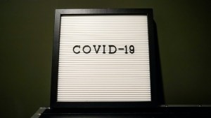 A white sign with a black frame and COVID-19 is written in the centre.