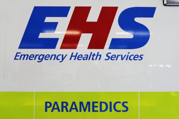 The Emergency Health Services (EHS) logo on a white ambulance. The E and S are royal blue, the S is red. Emergency Health Services is written below in italic font, and the word paramedics is below that in blue capital letters on a high visibility green stripe.
