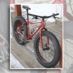 A photo of a red fatbike, which has fat nubby rubber tires.