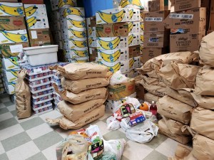 Stacks of bags of potatoes, banana boxes, and other food items.