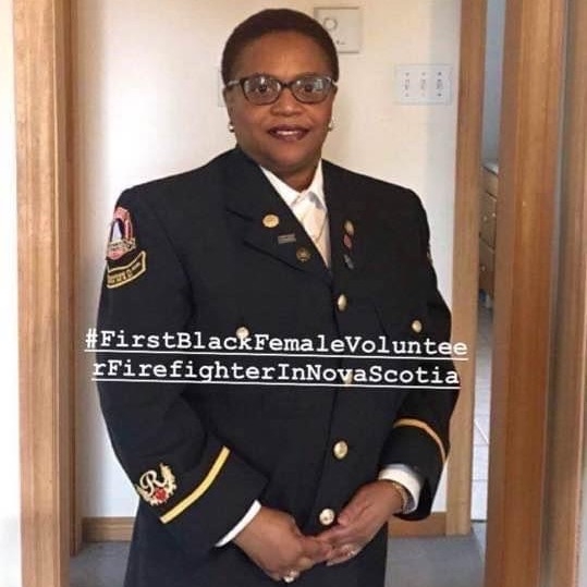 Black lady in glasses and fire department uniform smiles