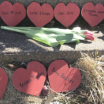 a memorial on church steps with red paper hearts and tulips