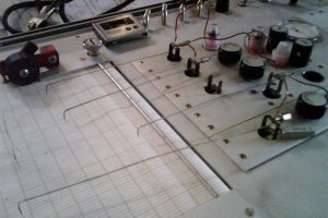A machine draws line on a sheet of gridded paper.