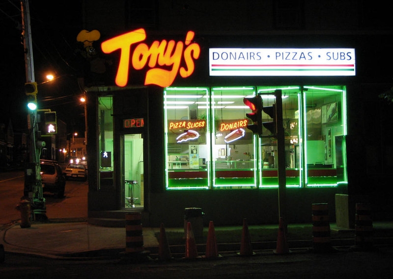 Storefront at night. A restaurant with a neon sign that says Tony's.