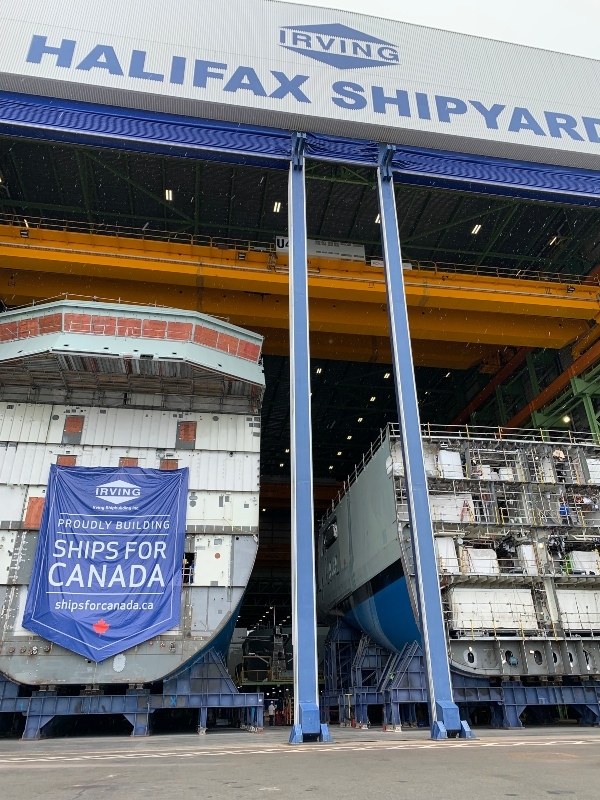 Two ship hulls in a dry dock with a banner that says Ships for CAnada.
