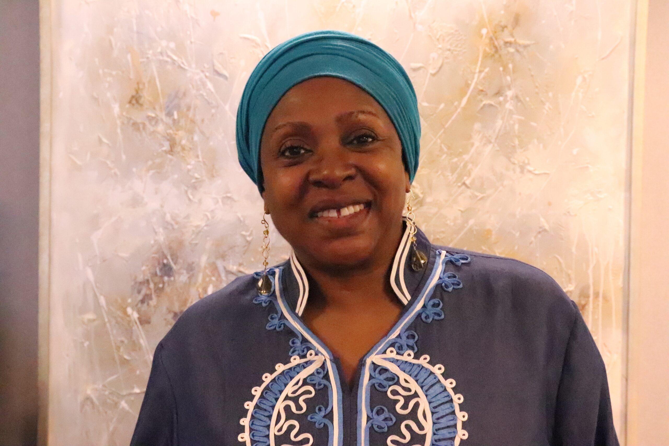 Black lady in blue head wrap smiles for the camera