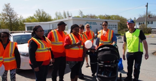 Community members in orange refective vests during a walk. One of the walkers has a stroller