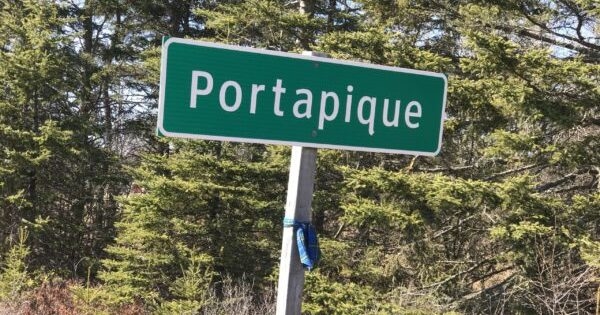 The green Portapique roadsign with a tartan sash tied on the post