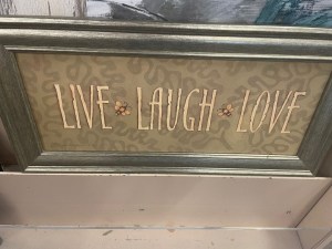 A framed home decor sign that says live, laugh, love in golden font