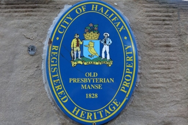 A blue plaque displayed on a cement wall