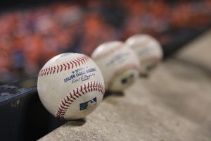 three Major League baseballs displayed on a cement rail